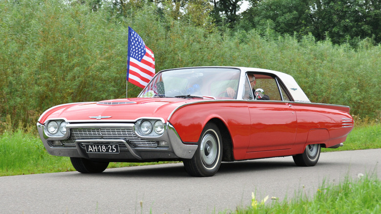 1961 Ford Thunderbird driving down street