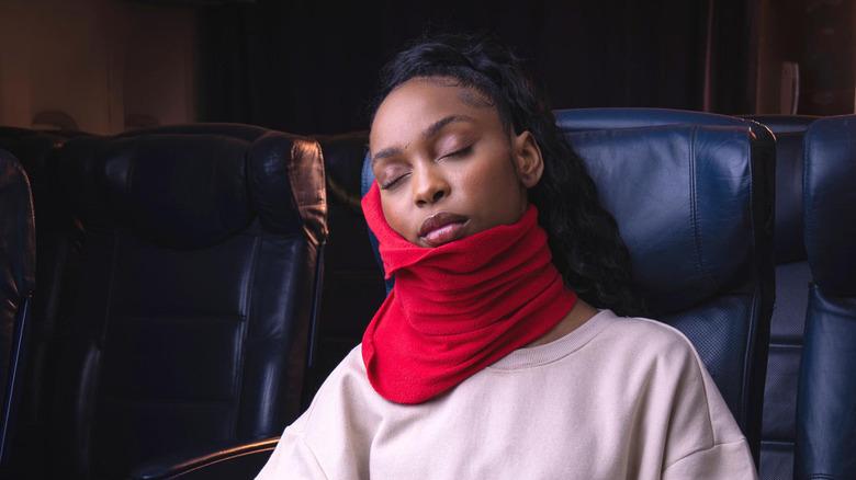 woman asleep with red trtl pillow on flight