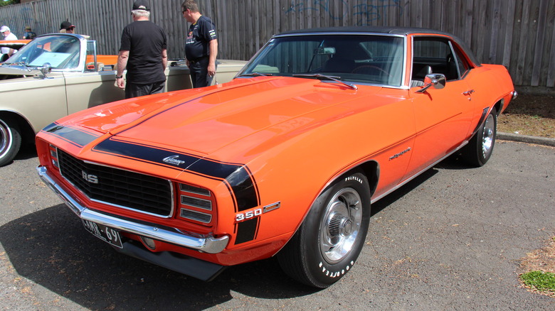 A Camaro RS in Hugger Orange parked at a car show