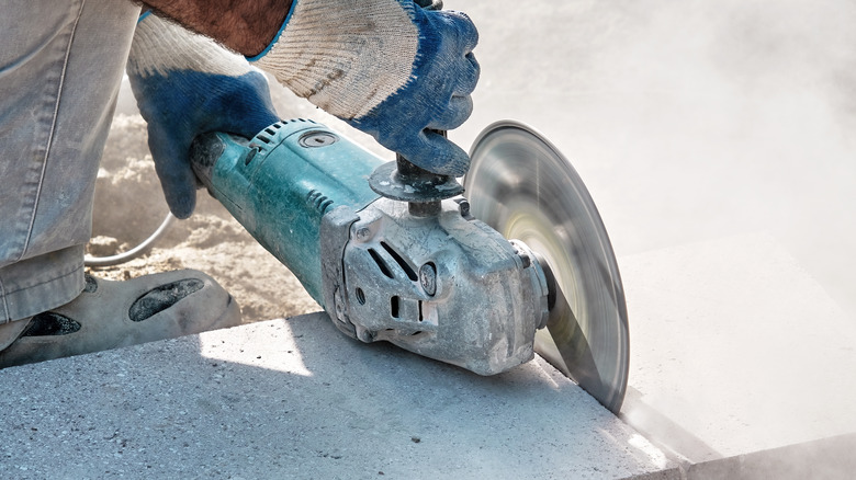 A man using an angle grinder to cut through tile.