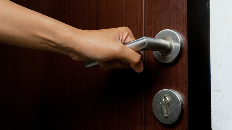 Hand opening a wooden door