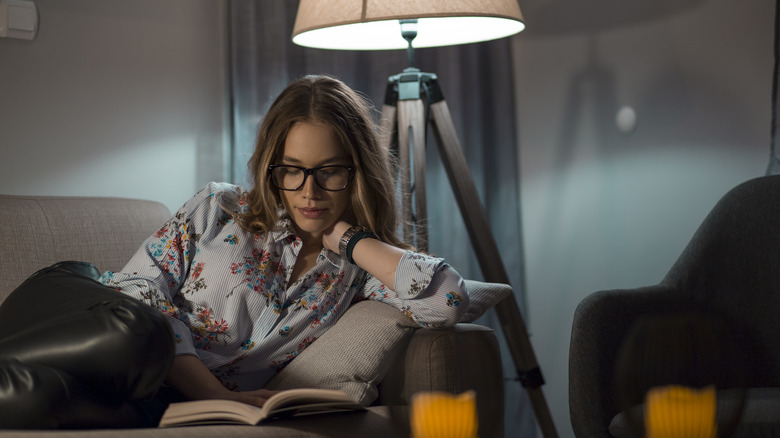 Woman reading on sofa next to lamp