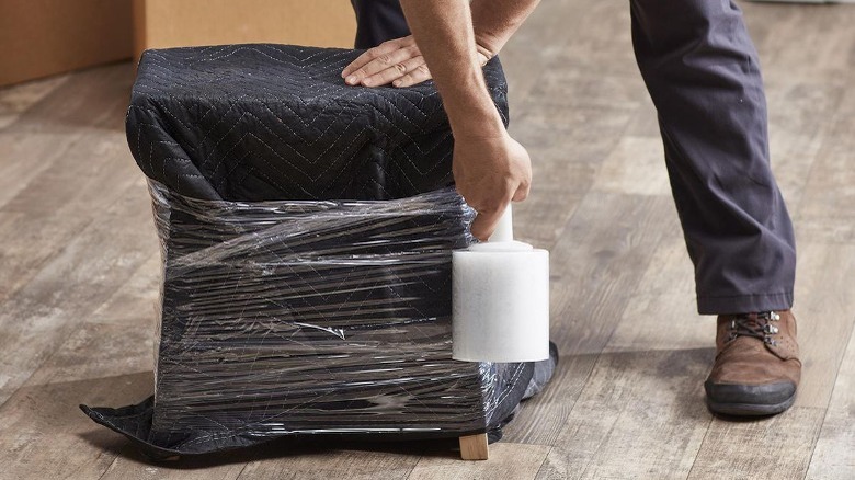 Person stretch wrapping footstool