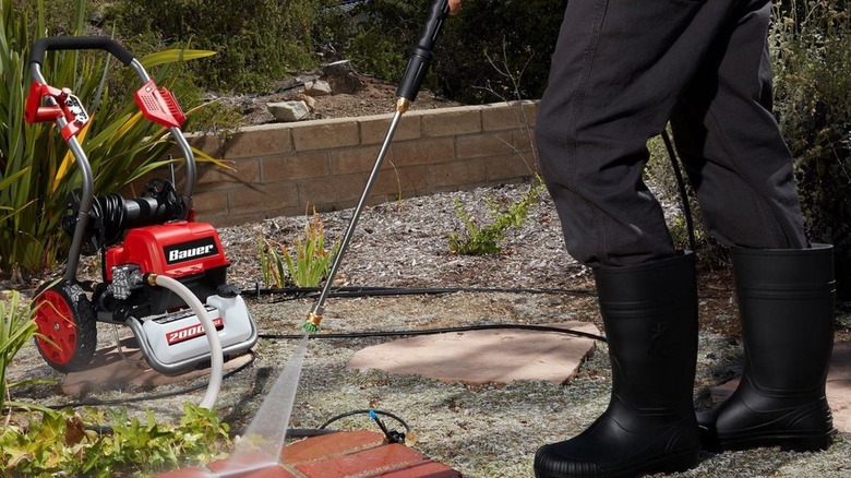 Person pressure washing bricks in a yard