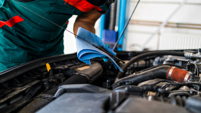 person measuring oil level in car