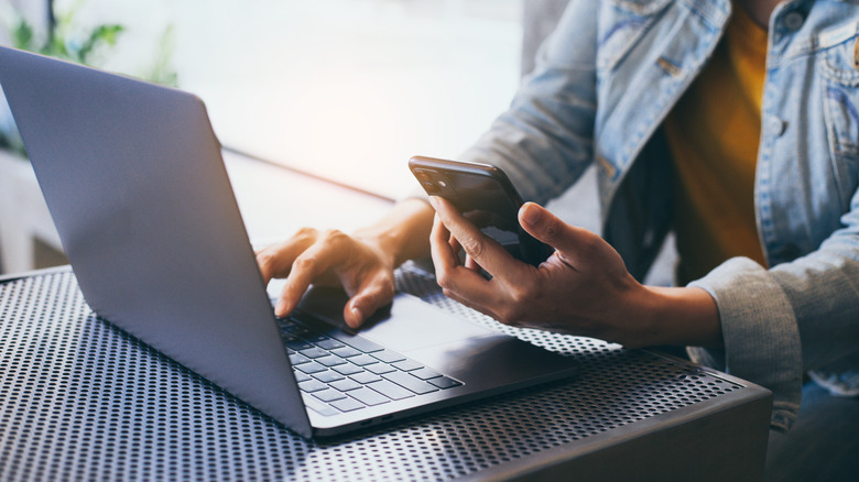 Person using smartphone and laptop