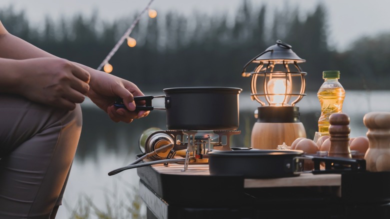 Person cooking next to a lake 