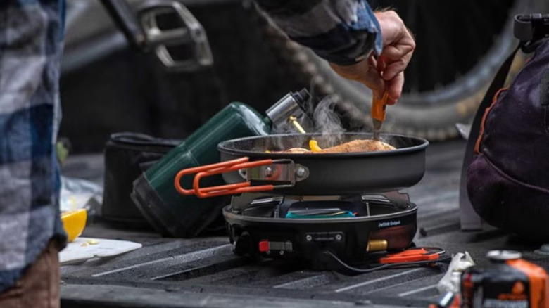 person cooking pan on truck tailgate