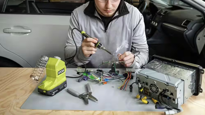 Person soldering wire from car stereo