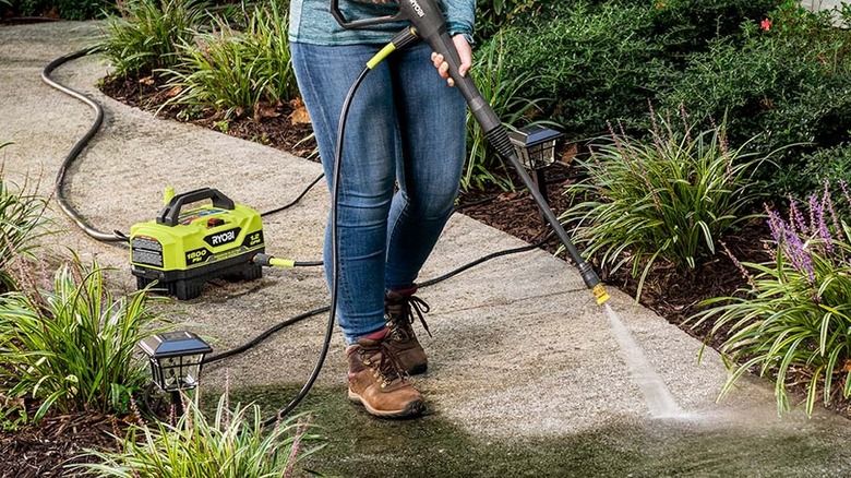 Person using pressure washer on patio