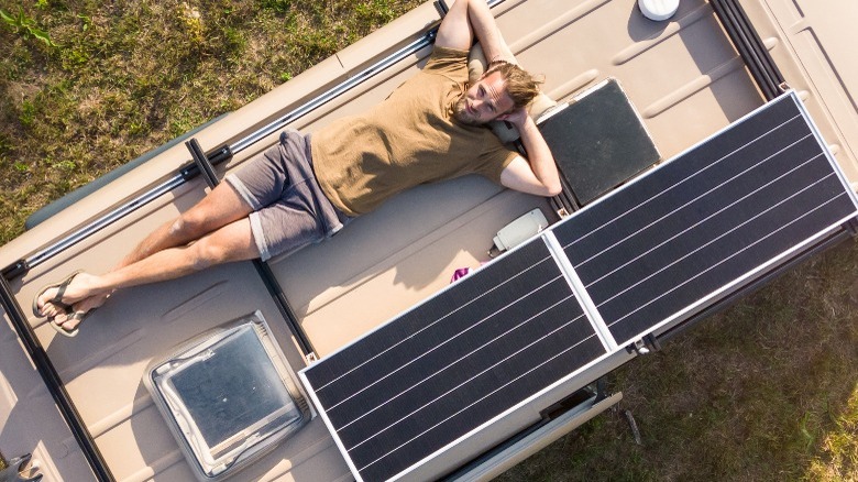 Man on top of van roof surrounded by solar panels