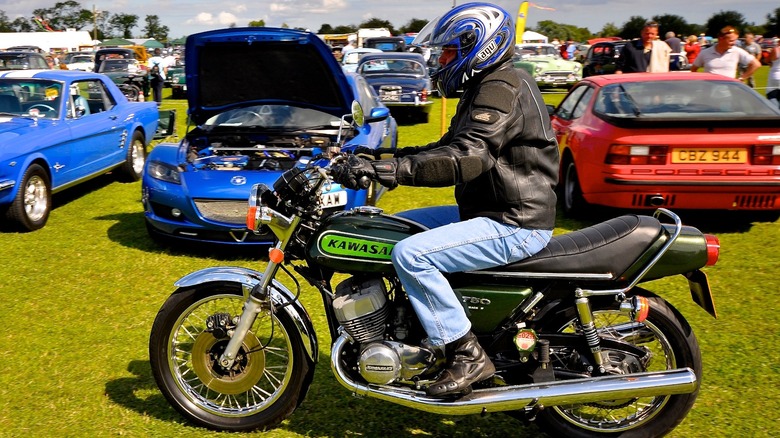 Helmeted rider on Kawasaki H2 Mach IV in grass parking lot