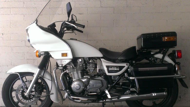 Kawasaki KZ1000 police motorcycle parked in front of white brick wall