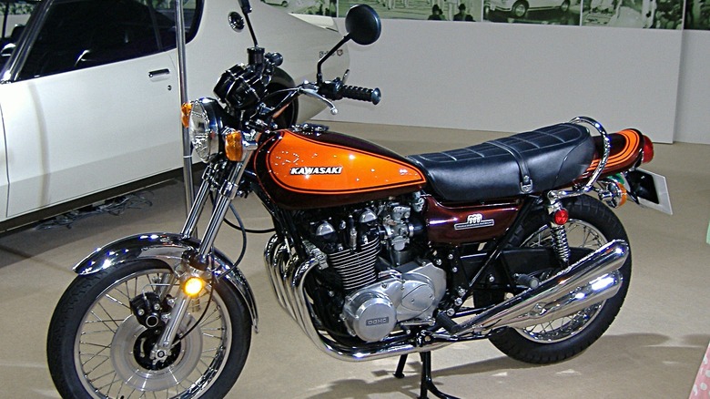 Kawasaki Z1 motorcycle parked indoors next to white sports coupe