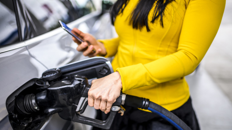 woman on phone pumping gas