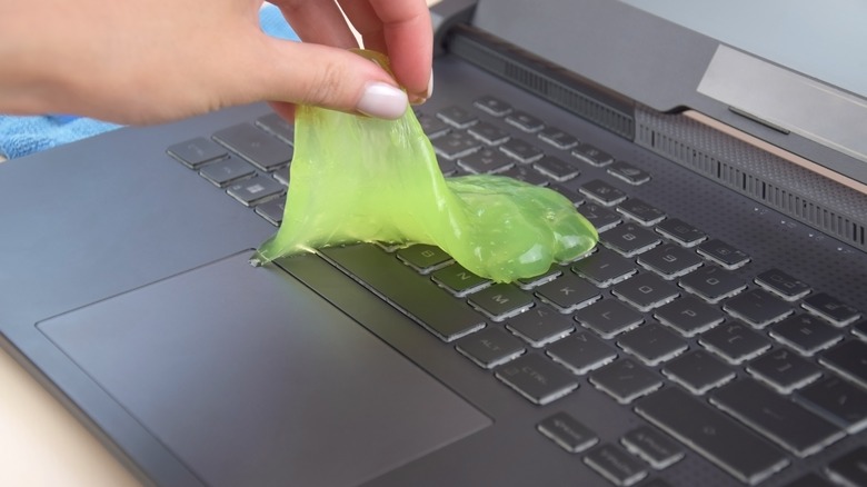 hand lifting cleaning gel from laptop keyboard