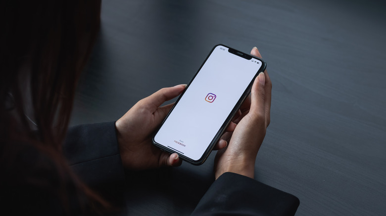 woman holding iPhone, Instagram logo on screen