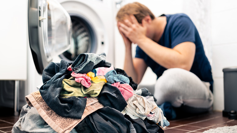 frustrated man near pile of laundry