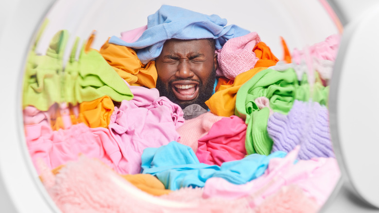 man overwhelmed by pile of laundry