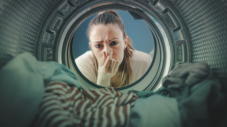 woman holding nose looking in washer