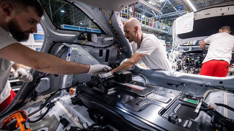 workers install a battery inside PHEV Kia