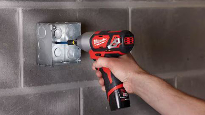 person using milwaukee cordless drill