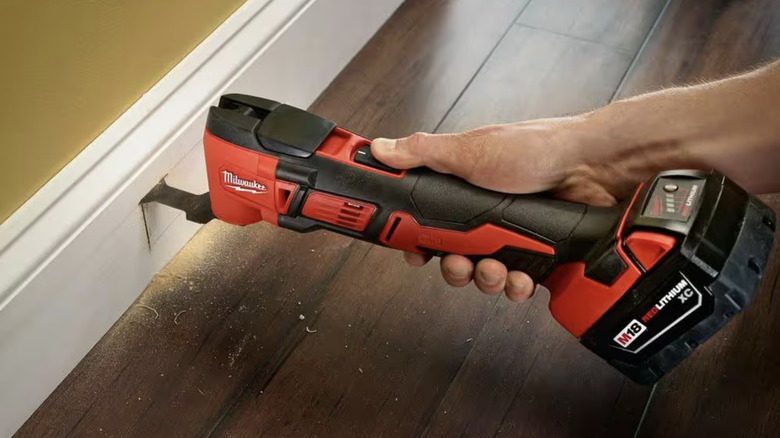 Person using oscillating tool to cut into baseboard