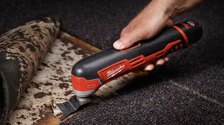 Person using an oscillating tool to scrape gunk off the floor