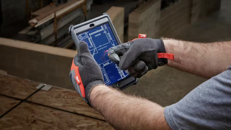 Person using tablet while wearing working gloves