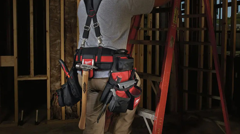 Person wearing tool belt with hammer hanging from it