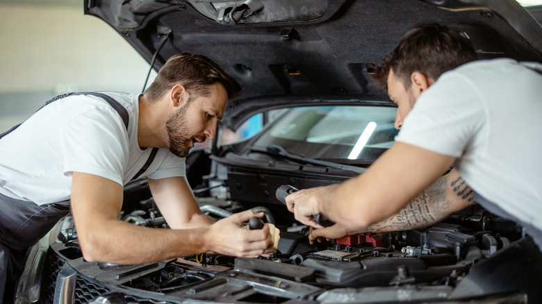 two people working on car engine