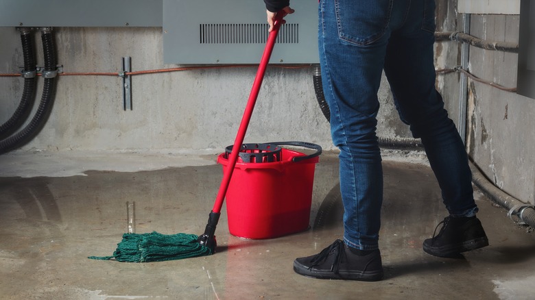 person mopping flooded basement