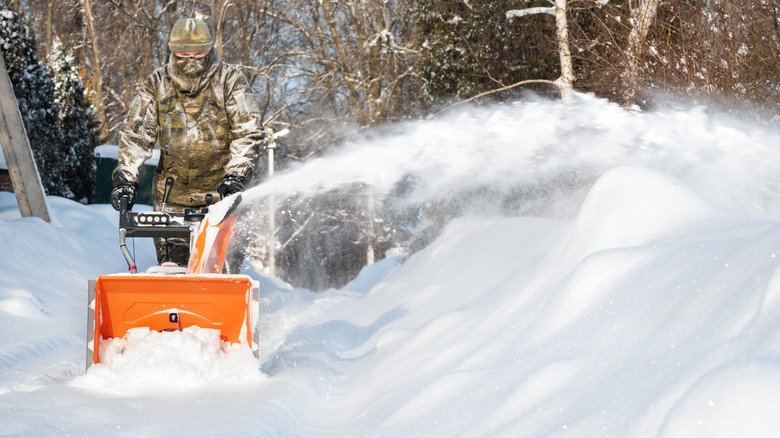 Man with snow blower launching snow