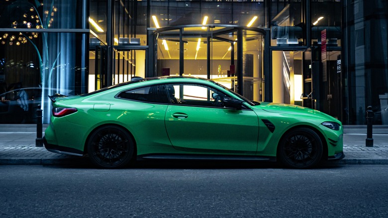 Green sports car parked in front of a modern building