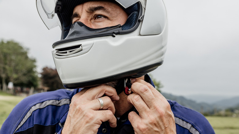 A man putting on a motorcycle helmet with an advanced ventilation system before hitting the road