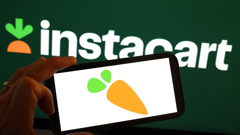 person holding up phone in front of Instacart sign