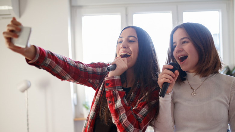 girls singing karaoke with phone