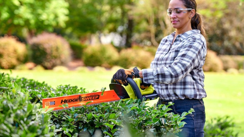 Woman using Ryobi hedge trimmer