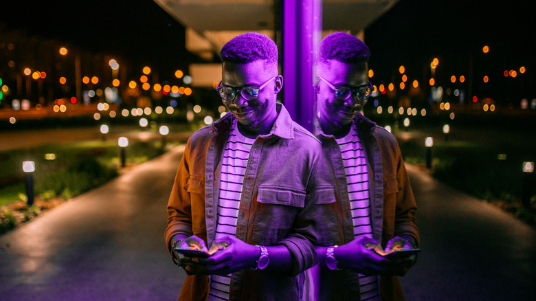 person at night with his reflection in a window with leading lines in the background