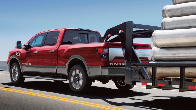 A red Titan XD towing a loaded gooseneck trailer