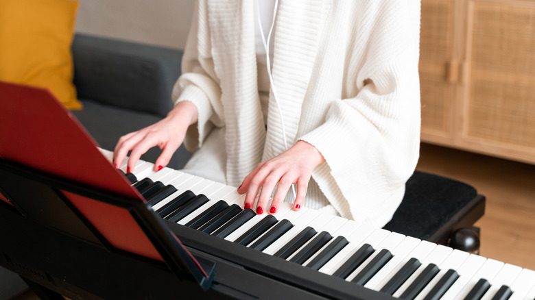 Woman playing electronic piano at home 