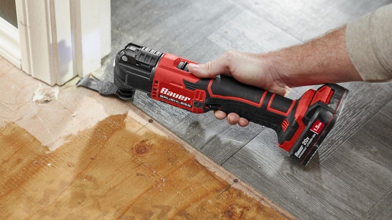 Person using an oscillating tool on a baseboard