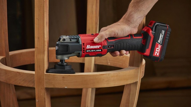 Person using an oscillating tool to sand a barstool