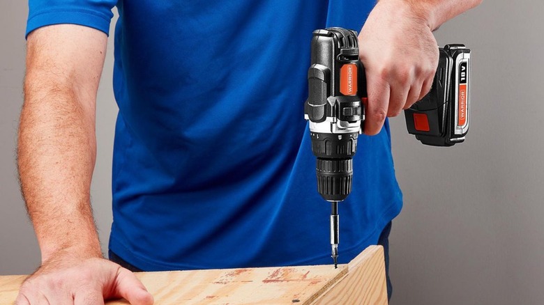 Person drilling a hole in a piece of wood