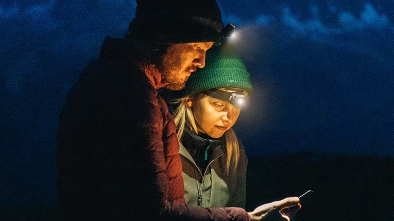 Two people in the dark outside with headlamps on