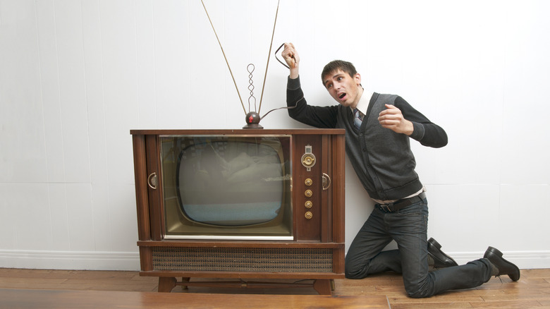 person adjusting rabbit ears tv antenna