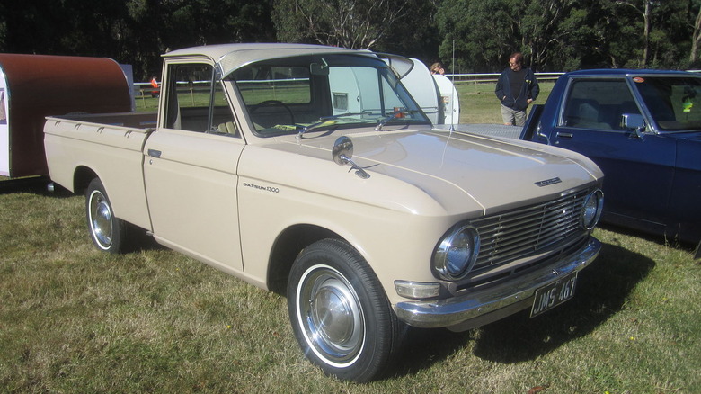 Tan Datsun 520 pickup with trailer attached parked in grass field