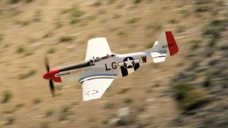 Tom Cruise flying P-51 Mustang World War II fighter over mountain with trees