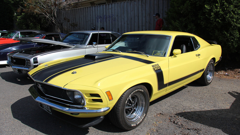 Yellow 2012 Boss Mustang parked in a row with other classic cars