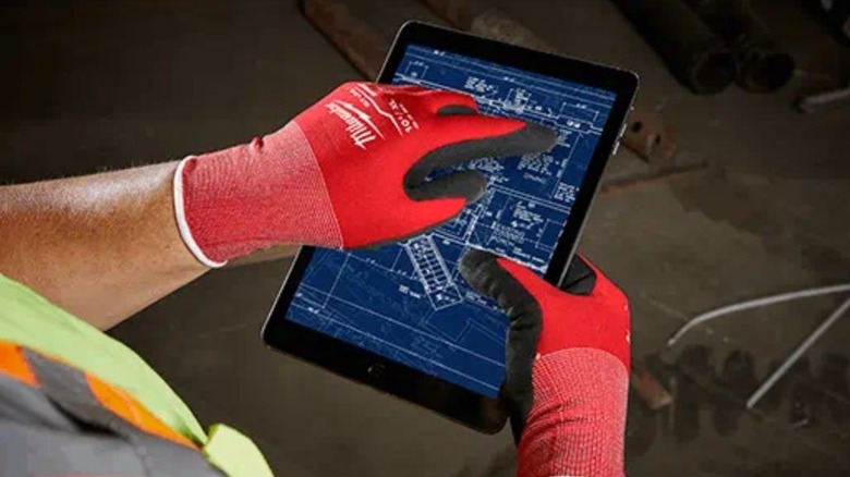 person using tablet with Milwaukee gloves